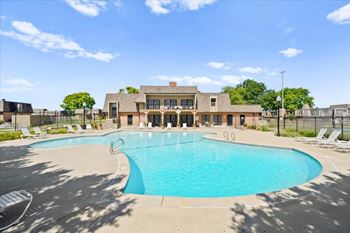 A large swimming pool in front of a building with a fence around it.